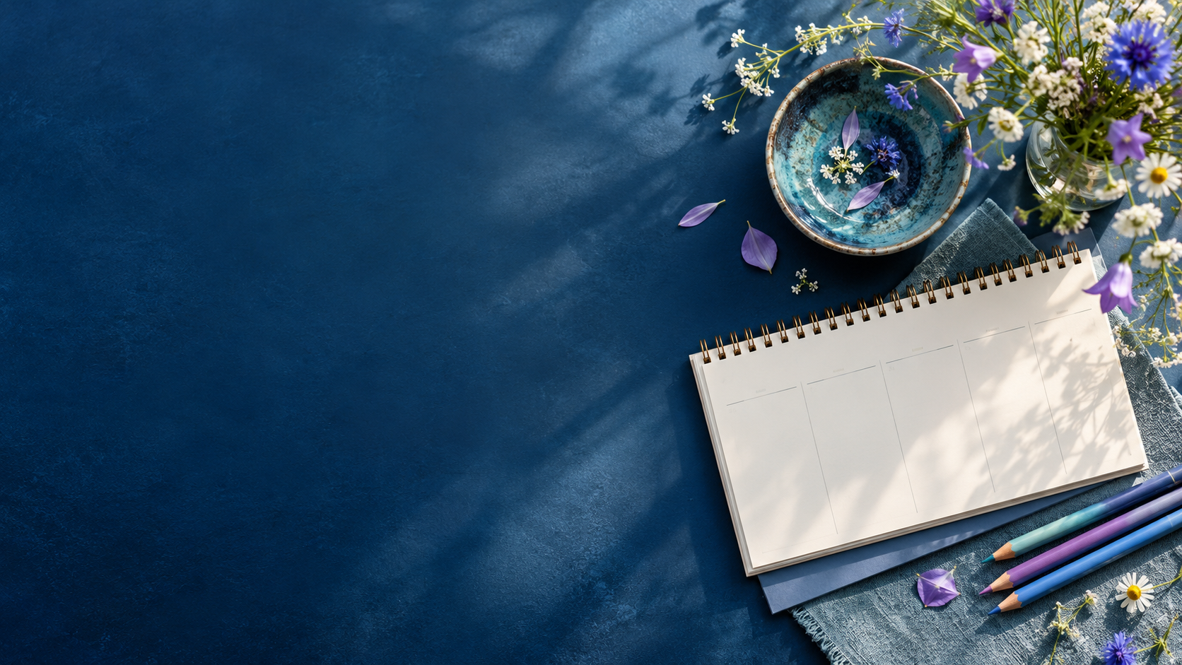 Planer, Stifte und Blumen auf blauem Schreibtisch